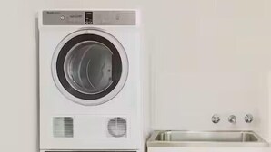 A stacked washer and dryer unit with a white cabinet below. - Loftberg Villas (Muswellbrook)