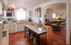 A spacious kitchen with a central island, a dining area with a wooden table, and a living space with a sofa. - Cozy home in Cadolive with private swimming pool, can be inside or outside (Cadolive)