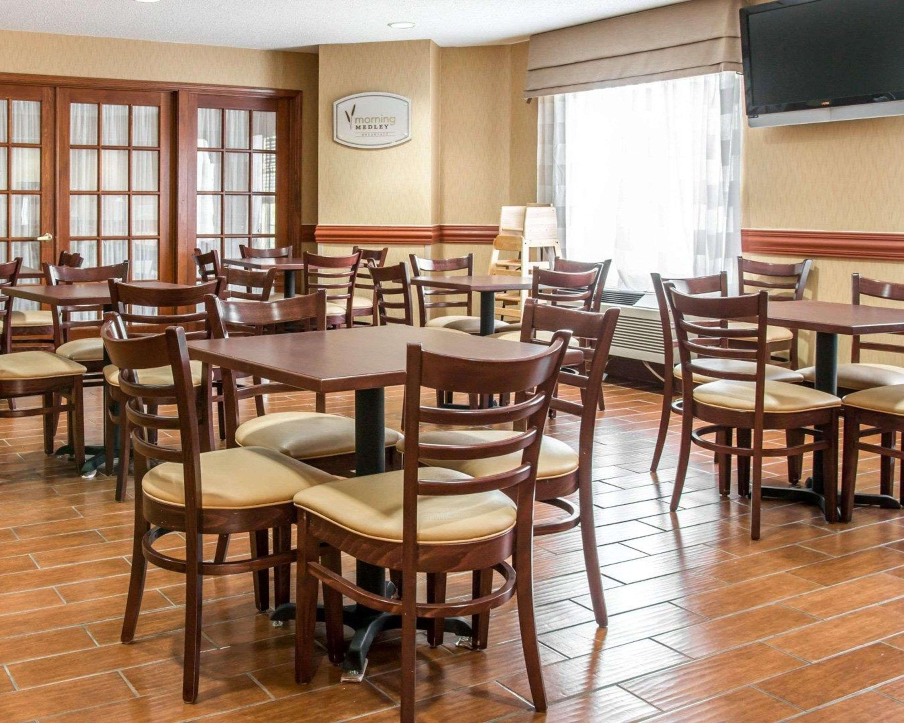 A hotel dining area with wooden tables and chairs, a large window with curtains, and a sign on the wall.