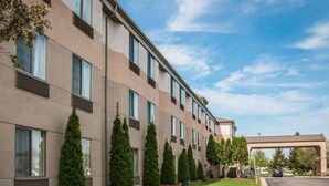 A multi-story hotel with a modern facade, a well-maintained lawn, and a covered walkway.