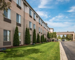 A multi-story hotel with a modern facade, a well-maintained lawn, and a covered walkway. - Sleep Inn & Suites (Grand Rapids)