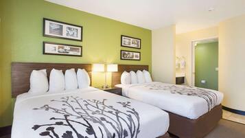 A hotel room with two beds, a nightstand with a lamp, and framed pictures on the wall.