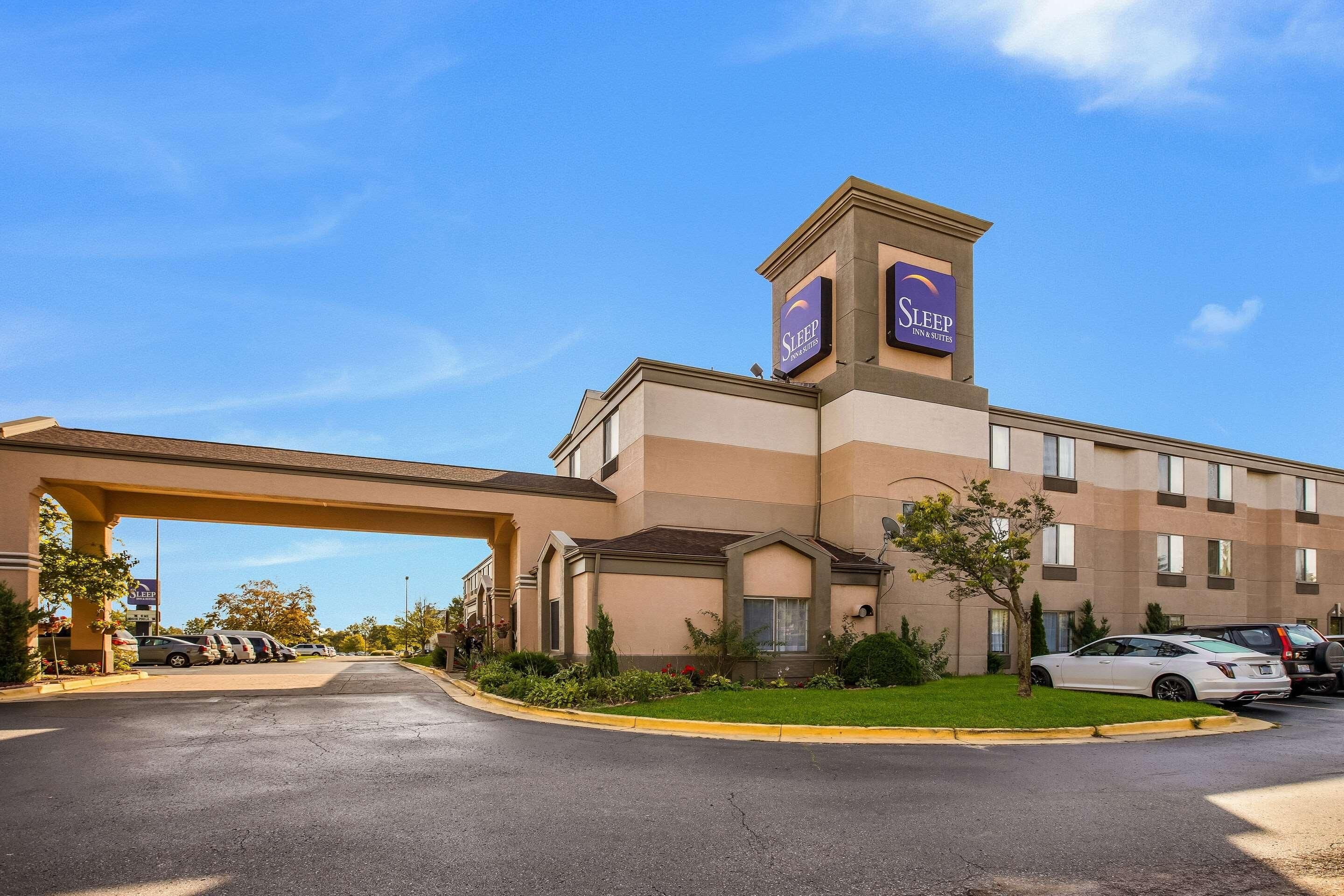 A hotel with a prominent Sleep Inn sign, a parking lot, and a well-maintained lawn.