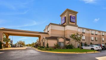 A hotel with a prominent Sleep Inn sign, a parking lot, and a well-maintained lawn.