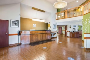 Et hotellets receptionområde med en træreception, et skilt med teksten 'SLEEP' og en trappe, der fører op til et højere niveau.