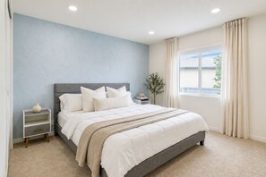 A bedroom with a bed, bedside tables, a nightstand, a window with curtains, and a plant. - The LA Garden House Retreat (Hawthorne)