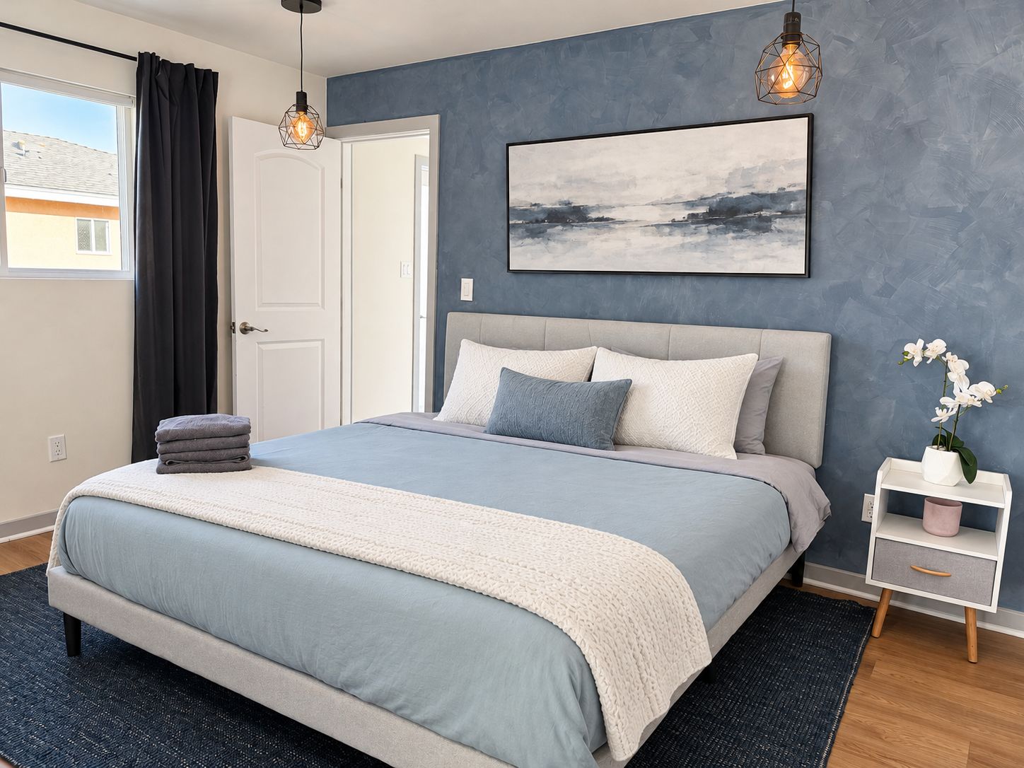 A modern bedroom with a bed, bedside table, and a painting on the wall.