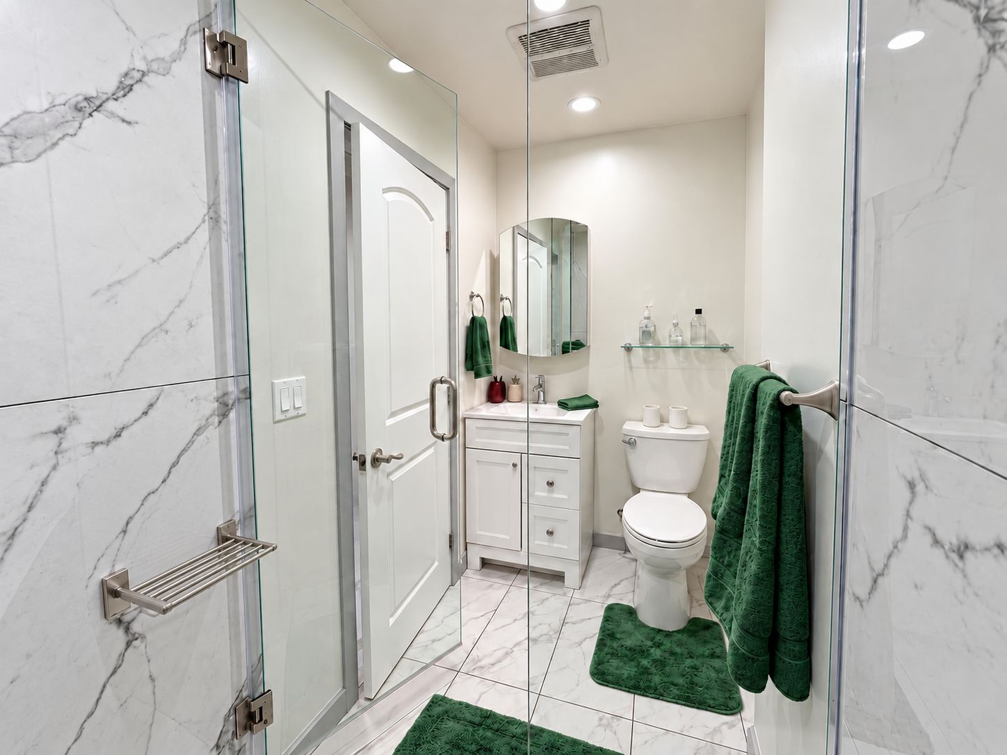 Un baño moderno con cabina de ducha de vidrio, paredes de mármol blanco, inodoro blanco y toallas verdes.