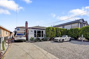 A residential driveway with two cars, a house, and a hedge. - The LA Garden House Retreat (Hawthorne)