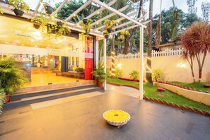 Un espacio al aire libre cubierto con macetas, un banco y un arreglo floral decorativo.