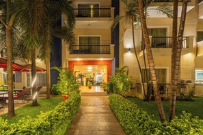 A hotel entrance with a paved pathway, palm trees, and outdoor seating. - Kyriad Prestige Calangute Goa by Othpl (Calangute)