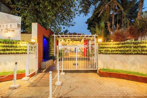 A gated entrance with a pergola, potted plants, and a pathway leading to a building. - Kyriad Prestige Calangute Goa by Othpl (Calangute)