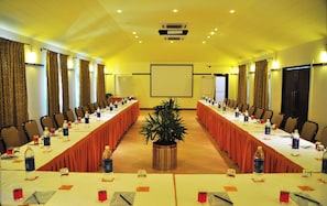 A conference room with long tables, chairs, water bottles, and a potted plant. - Kyriad Prestige Calangute Goa by Othpl (Calangute)