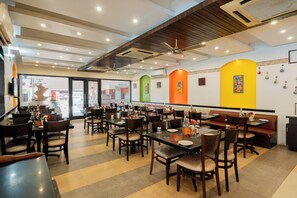 A restaurant interior with multiple dining tables and chairs, ceiling fans, and a large window.