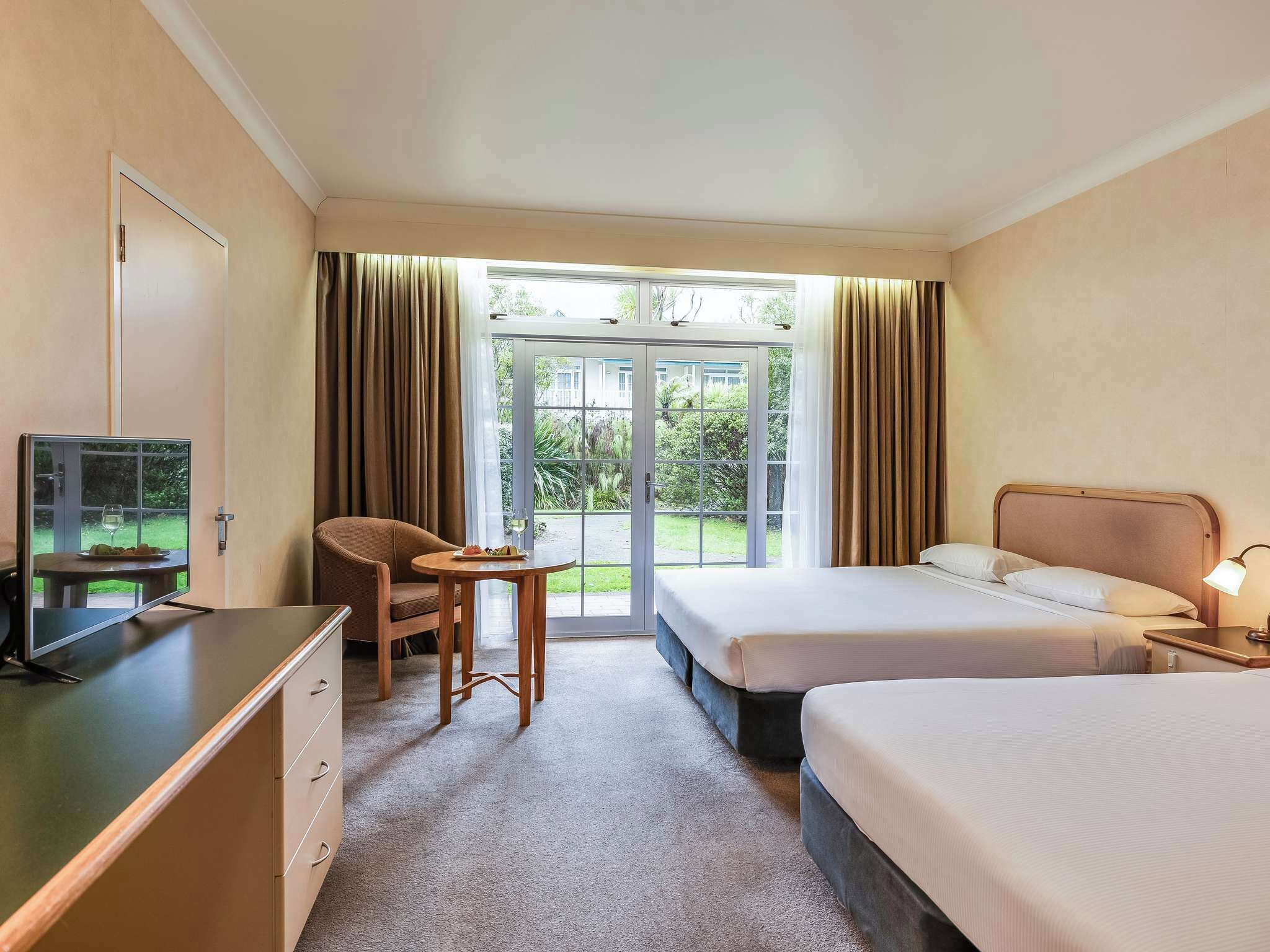 Ein Hotelzimmer mit Bett, Schreibtisch, Stuhl und Fernseher.