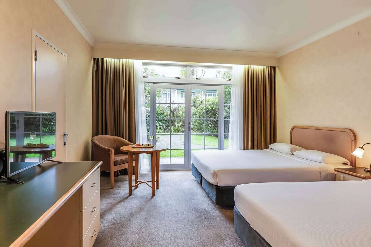 Una habitación de hotel con cama, escritorio, silla y televisor.