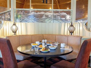 A dining area with a round table, cushioned seating, and a stained glass window above. - Wairakei Resort Taupo (Wairakei)