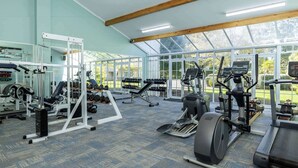A gym with cardio machines, weightlifting equipment, and a large window offering a view of the outdoors. - Wairakei Resort Taupo (Wairakei)