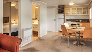 A compact hotel room with a bed, a small kitchenette, a dining area with a table and chairs, and a separate bathroom. - Wairakei Resort Taupo (Wairakei)