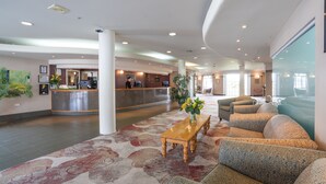 A spacious lobby with a reception desk, seating area, and a large window.