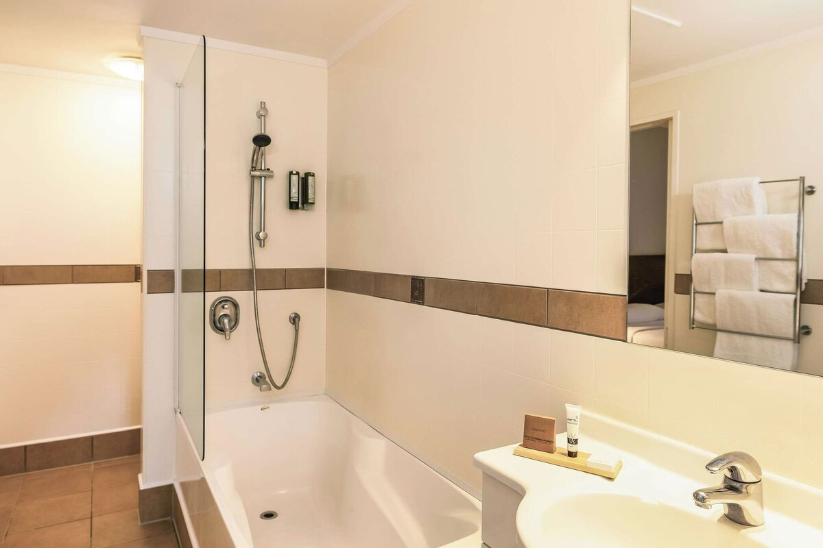 Un baño con bañera, ducha, lavabo y un perchero para toallas.