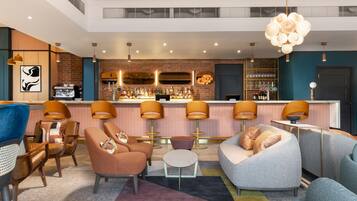 A bar area with a brick wall, bar stools, and a variety of bottles.