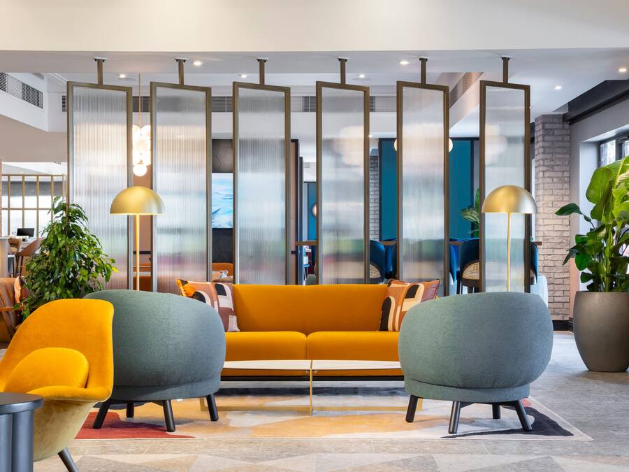 A modern lobby with a sofa, chairs, and a plant.