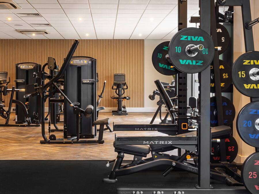 A gym with various exercise equipment, weightlifting racks, and a wooden floor.