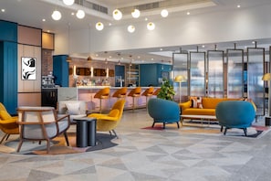A modern bar area with seating, a counter, and a decorative plant. - Voco Fareham-solent (Fareham)