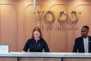 A reception desk with a sign reading 'YOCO BY THE RIVER'. - Voco Fareham-solent (Fareham)