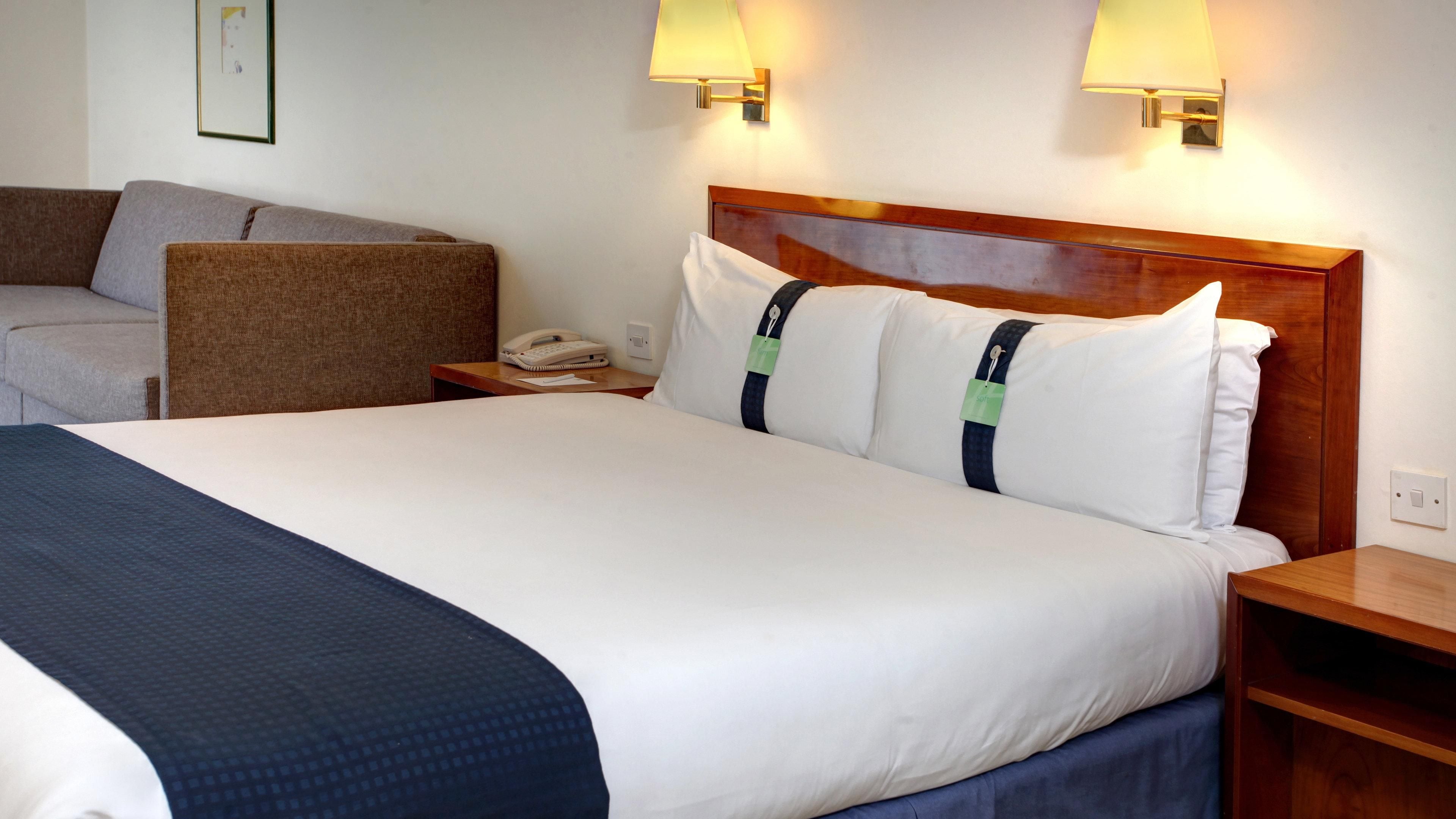 Habitación de hotel con una cama grande, dos lámparas de noche, un teléfono en la mesita y una pequeña mesa.