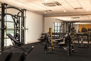 A gym with weightlifting equipment, benches, and dumbbells.