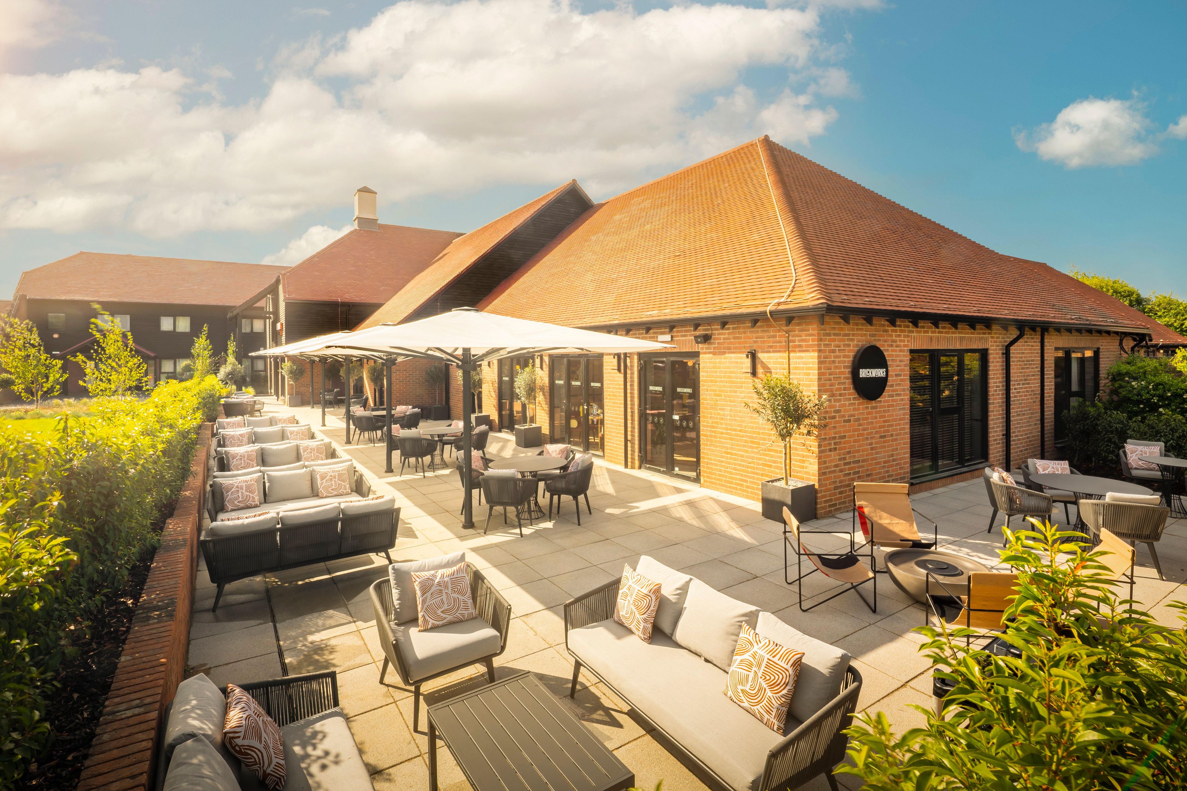 A patio area with outdoor seating, a brick building, and a clear sky.