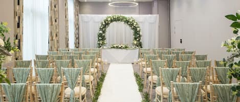 A wedding ceremony setup with a floral arch, aisle, and rows of chairs.