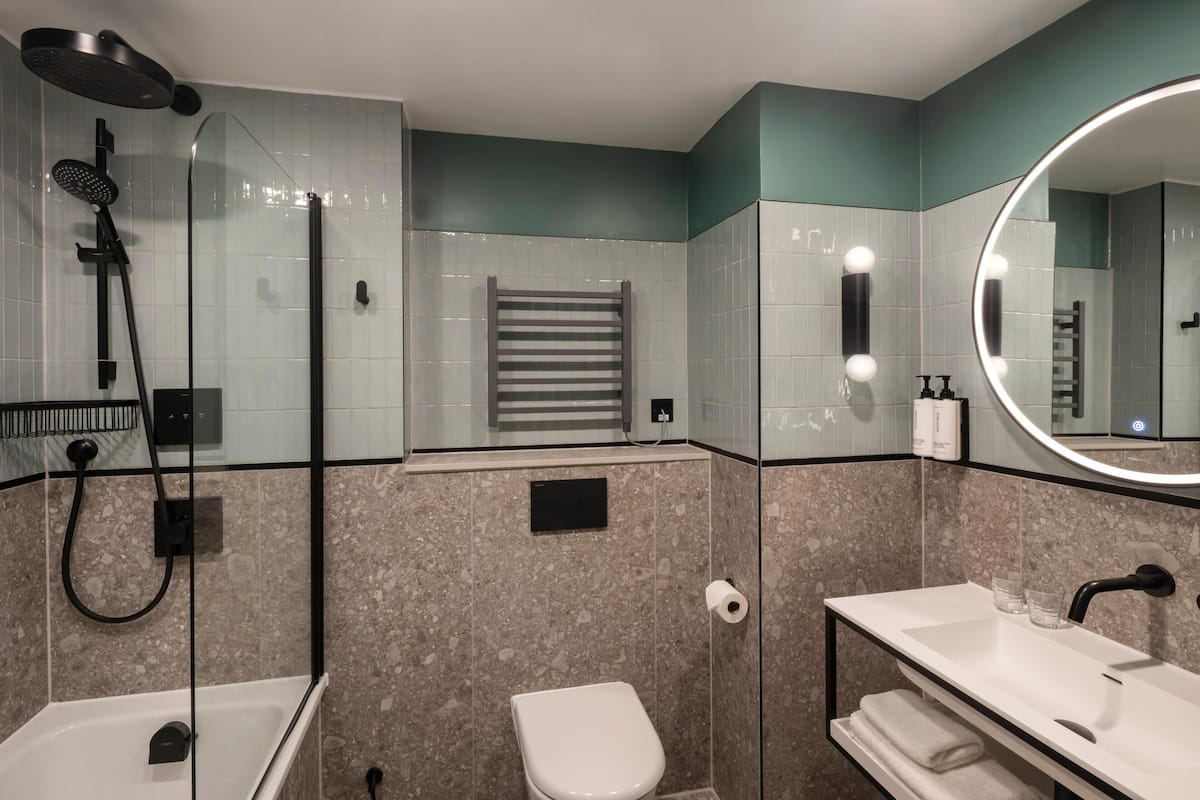 A modern bathroom with a glass-enclosed shower, a white toilet, a vanity with a mirror, and a towel rack.
