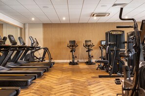 Un gimnasio con cintas de correr, elípticas y equipo de pesas.