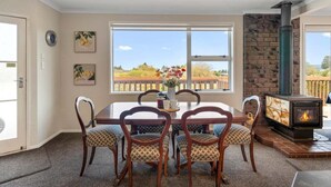 Zona pranzo con tavolo, sedie, camino e vista sull'esterno.