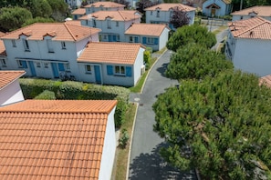 A residential area with white houses and red-tiled roofs, arranged in a grid pattern with a central narrow street.