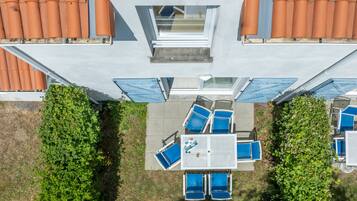 An aerial view of a building with a rooftop terrace, a table with chairs, and a small garden area.