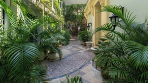 A courtyard with potted plants, a stone pathway, and a building facade with balconies. - Panna Villas Udaipur (Udaipur)