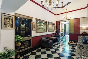 A hotel lobby with a checkered floor, framed artwork on the walls, and a chandelier. - Panna Villas Udaipur (Udaipur)