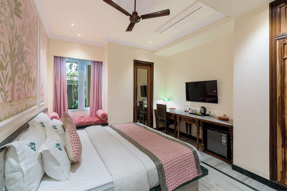 A hotel room with a bed, a desk, a television, and a ceiling fan.