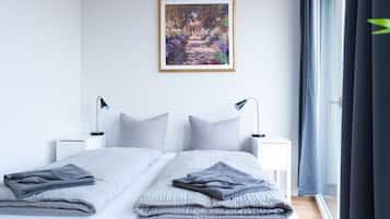 A modern bedroom with a large bed, two bedside tables, a framed painting, and a window with curtains.