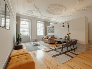 A spacious living room with a sofa, a dining table with chairs, and a large window providing natural light. - Apartment  by Interhome (Porto)