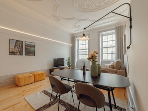 Ein modernes Wohnzimmer mit Esstisch, Sofa und Kunstwerk an der Wand.