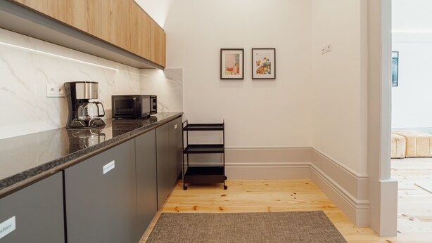 A modern kitchen with a coffee maker, microwave, and a black metal shelf. - Apartment  by Interhome (Porto)