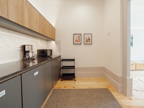 A modern kitchen with a coffee maker, microwave, and a black metal shelf. - Apartment  by Interhome (Porto)