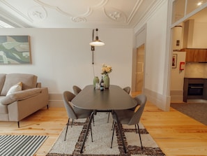 Ein modernes Wohnzimmer mit Esstisch, Sofa und einer Küche im Hintergrund.
