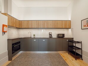 A modern kitchen with grey cabinets, a wooden countertop, a built-in oven, a coffee maker, and a microwave. - Apartment  by Interhome (Porto)