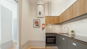 A modern kitchen with a built-in oven, a stainless steel sink, and wooden cabinets. - Apartment  by Interhome (Porto)